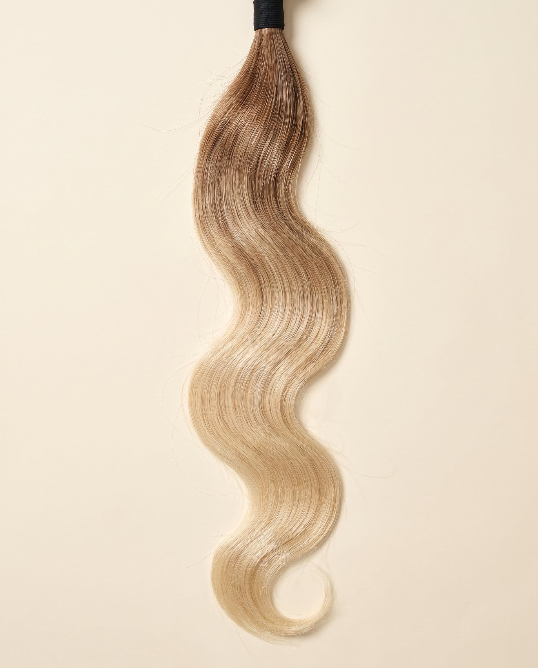 Human hair bundle in color A-5T/613 laid flat on a warm ivory background
