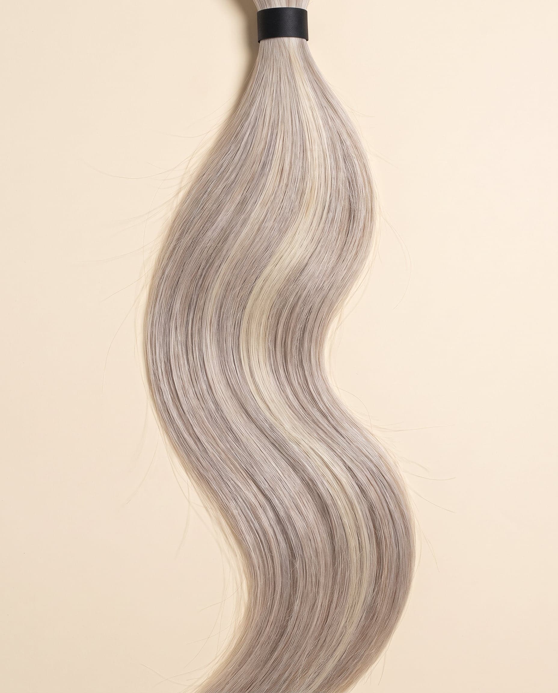 Human hair bundle in color A-NORVEGIAN/613 laid flat on a warm ivory background